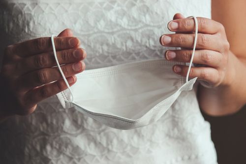 Bride Holding Face Mask by Straps