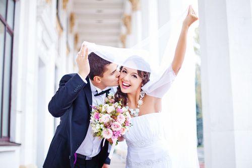 Couple Kissing and Laughing Under a Veil