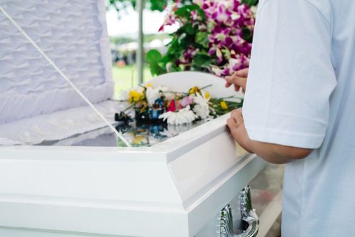 Person Putting Flowers on a Coffin