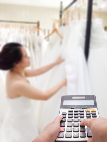 Woman Looking at Wedding Dresses With a Calculator in the Foreground