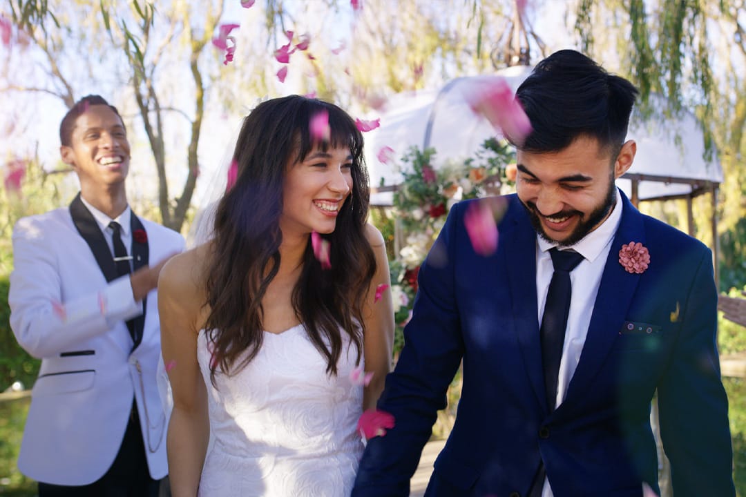 Newlywed couple laughing as they walk down the aisle.