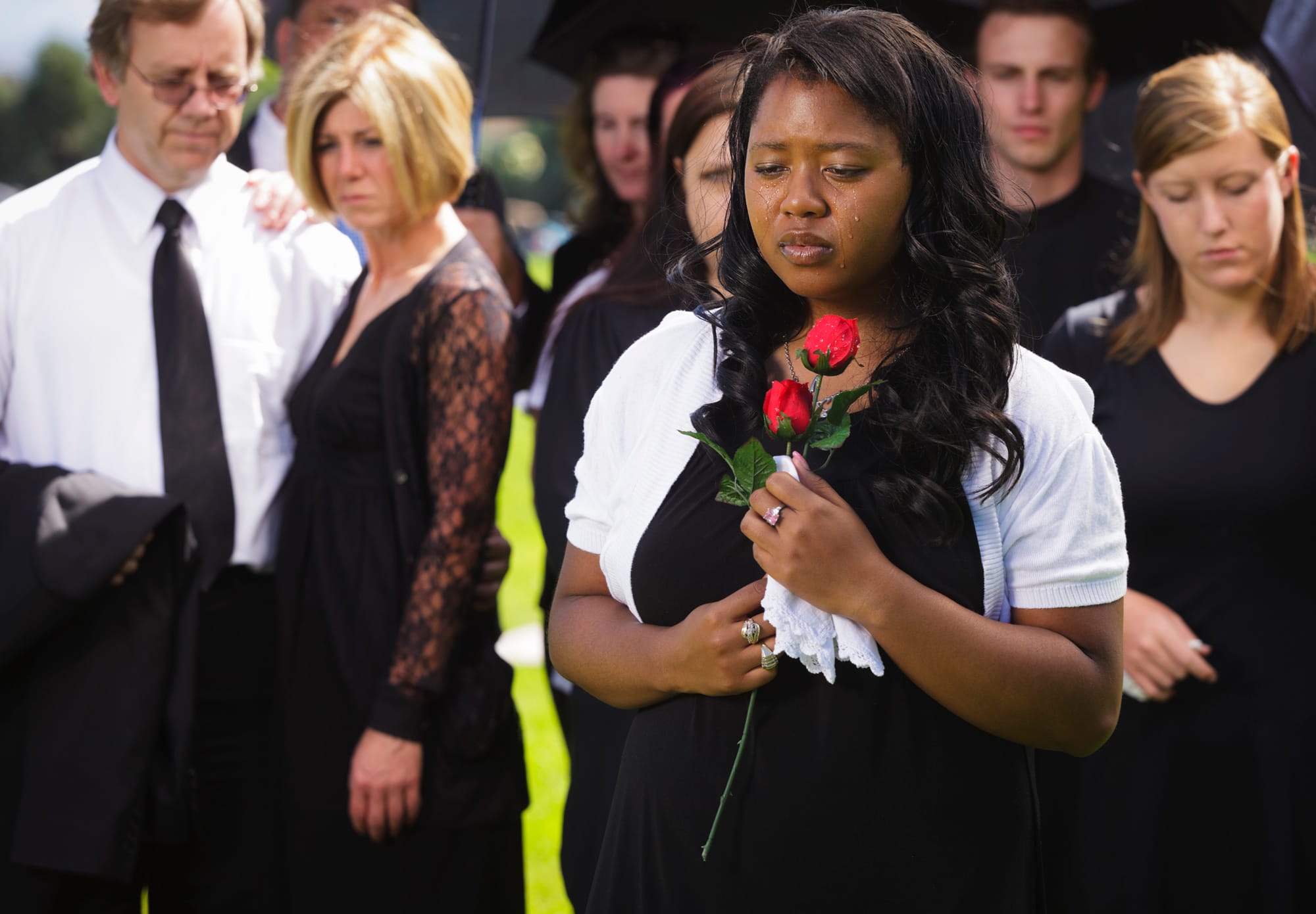 African-American minister of the Universal Life Church Ministries holding rose and crying at funeral